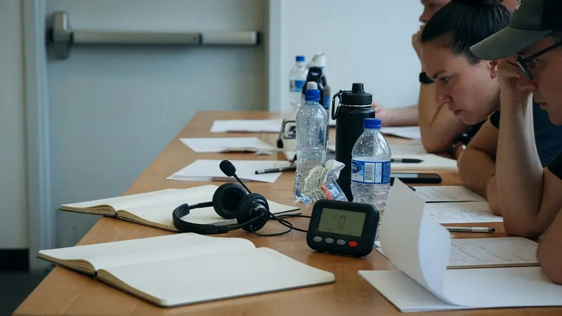 Coaches and players at a draft preparation table with blank notepads